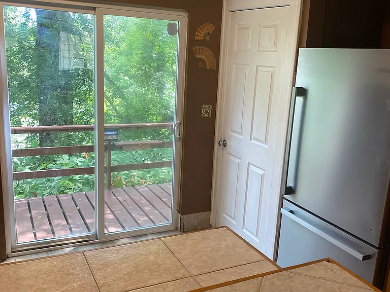 Living room looking into kitchen with new ss refrigerator white door leads to full basement.