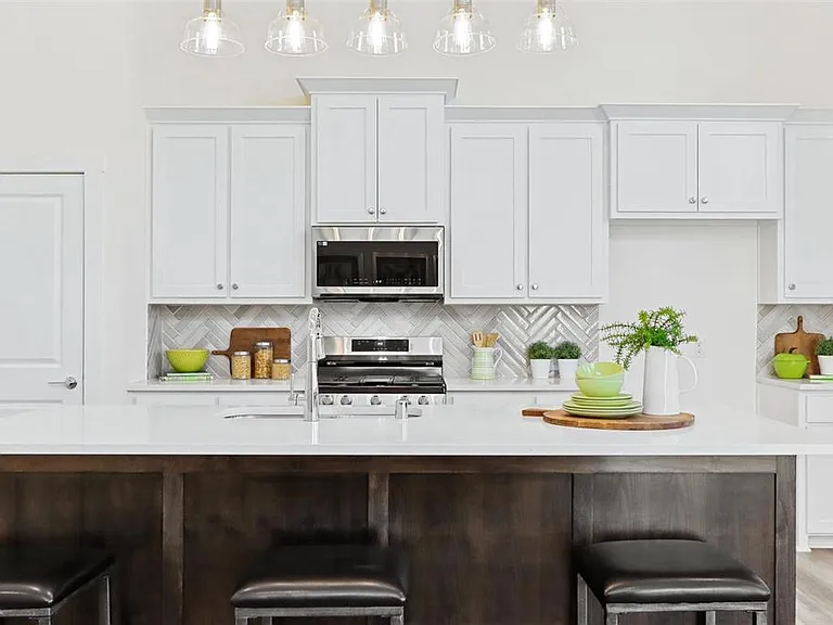 The modern kitchen features a spacious island, ample cabinet and counter space, and comes complete with full size refrigerator.