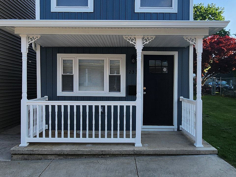 FRONT OF HOUSE WITH NEW SIDING AND RAILINGS.