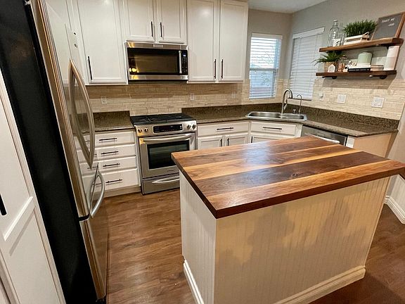 Renovated kitchen with walnut butcher black ad travertine backsplash