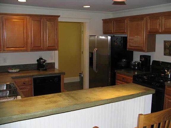 Renovated kitchen, concrete counter, stainless fridge, gas stove.