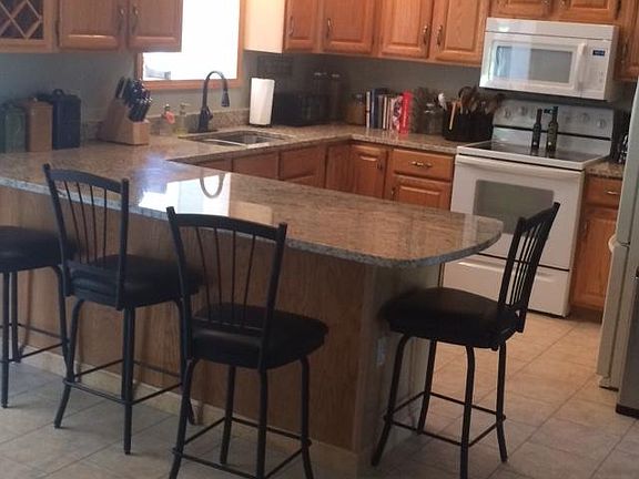 Kitchen, includes refrigerator, electric stove, microwave, dishwasher, wine rack, granite countertop. Tile floor