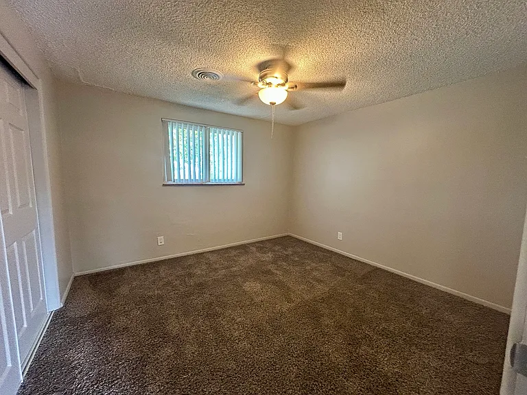 Inviting bedroom with cozy carpet, a ceiling fan, and ample natural light from a large window. Inviting bedroom with cozy carpet, a ceiling fan, and ample natural light from a large window.