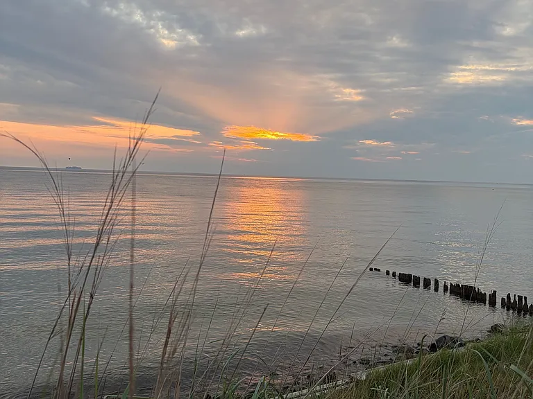 Sunrise over the water in front of the 1950s era beach cottage for rent near Burgess, Virginia