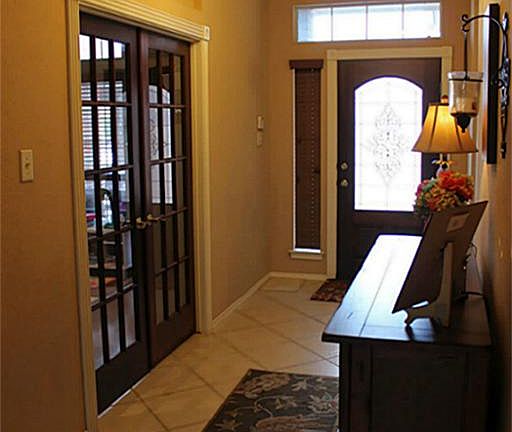 View of mahogany front door and stained French doors that lead to large study