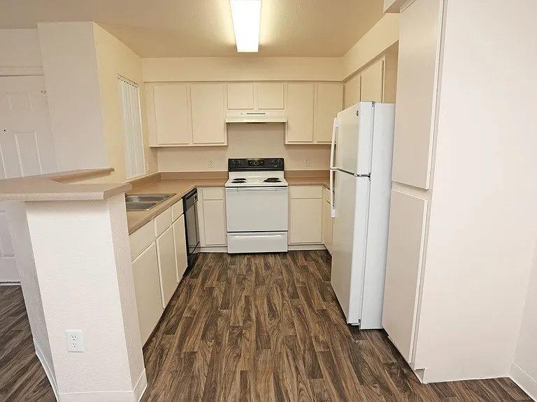 Open kitchen with wood-like flooring and white appliances