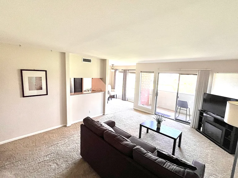 Living room with a private balcony with a view of the Strip and golf course. Incudes sleeper sofa, tv with a stand, WiFi router, coffee table, lamp, picture on the wall, decorative pillows