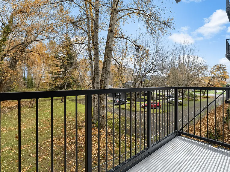 Cozy apartment balcony view framed by vibrant fall trees and community grounds. Cozy apartment balcony view framed by vibrant fall trees and community grounds.
