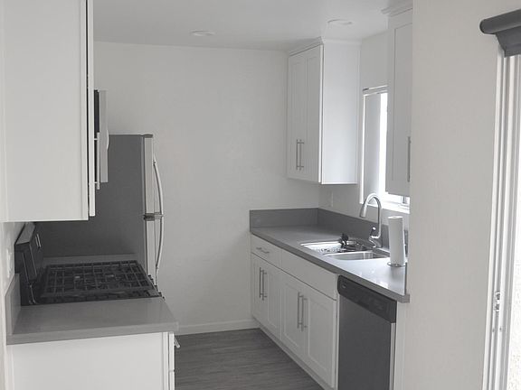 White cabinets with grey quartz counters, gas stove, dishwasher and microwave.