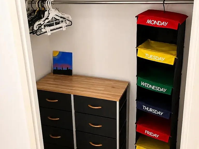Organized closet space with a hanging rod, upper shelf, and dresser for convenient clothing and accessory storage.