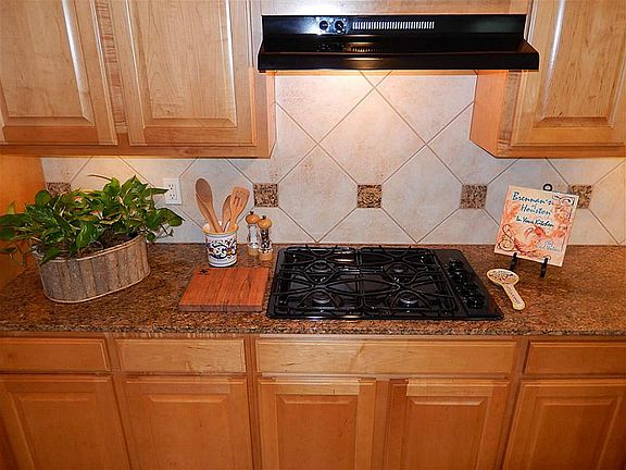 Gas range in the kitchen. Notice the tile back splash and new vent hood.