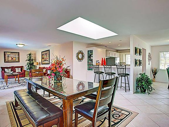 Large great room with 2 dining areas, kitchen bar with 3 stools, 1 arm chair, 2 sofas, 1 loveseat and a 60 inch flat screen TV.