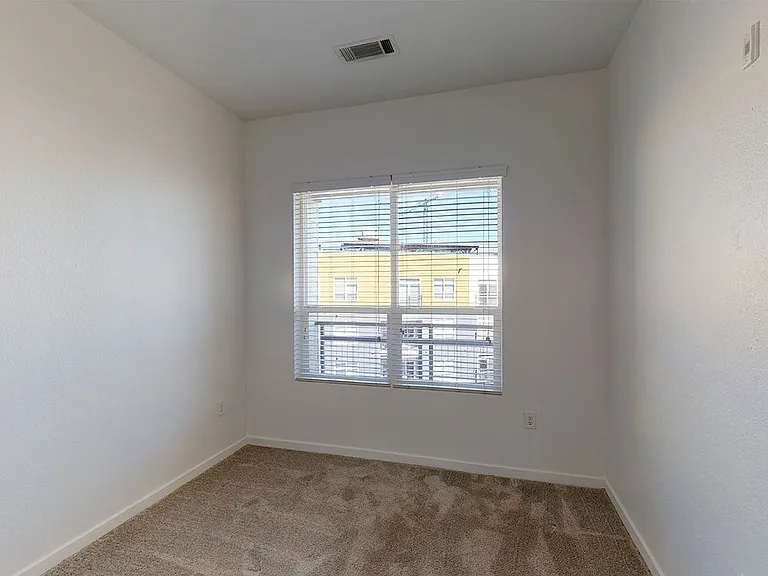 Spacious apartment bedroom with plush carpet flooring.