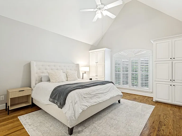 Vaulted ceiling with a ceiling fan, hardwood flooring, and white built-in cabinetry featuring black hardware