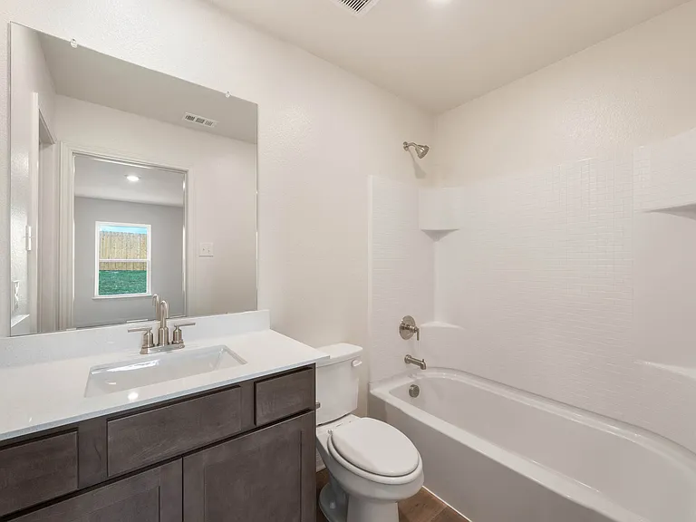 The master bathroom has a large vanity space and a shower-tub combo.