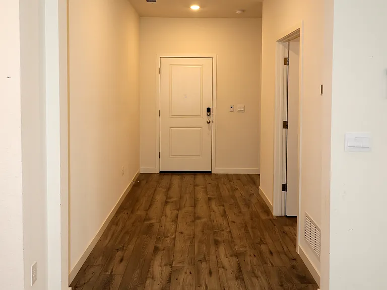 Looking down the hallway that leads to the front door. The door on the right halfway down the hall is the entrance to the laundry room.