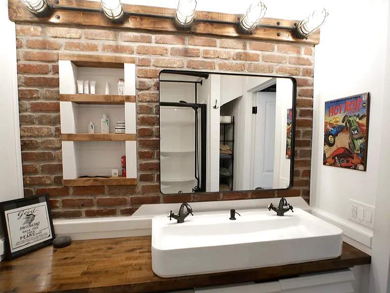 Custom main bath suite. Features: Sliding mirror for hidden storage, built in recessed shelving, dimmable lighting, double sink basin, linen closet, and oversized tub/shower combo with custom showerheads.