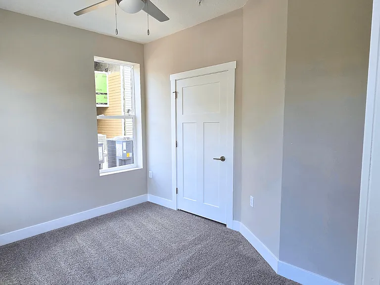 A carpeted bedroom with ceiling fan of an available apartment home at Greenwood Commons Apartments in Delaware, OH.