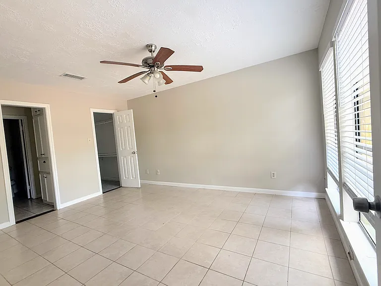 Generously sized primary bedroom with tile flooring overlooking the backyard.