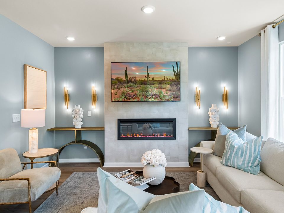 Bright blue family room with beige sectional and electric fireplace in townhome by DRB Homes in Cony