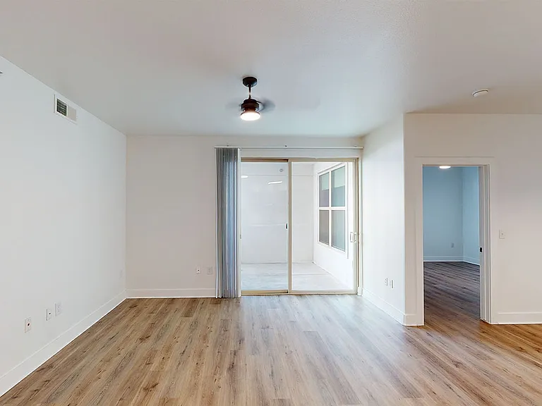 Apartment living room with wood-style flooring and balcony or patio in select homes.