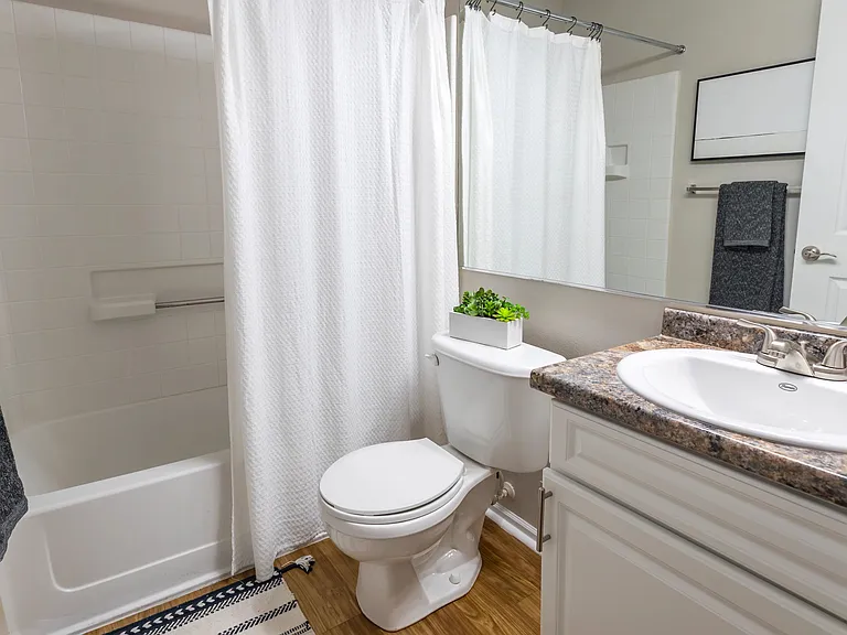 Bathrooms featuring sleek granite-inspired countertops, updated fixtures, a large mirror, and a full-size tub with shower.