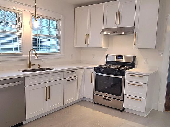 Kitchen w/ new cabinetry and stainless-steel appliances. Brushed gold cabinet hardware and sink faucet.