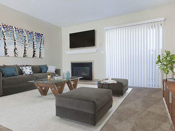 Carpeted and staged living room with fireplace and sliding doors.