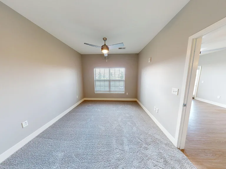 The primary bedroom includes a large window, ceiling fan, and carpet. The primary bedroom includes a large window, ceiling fan, and carpet.