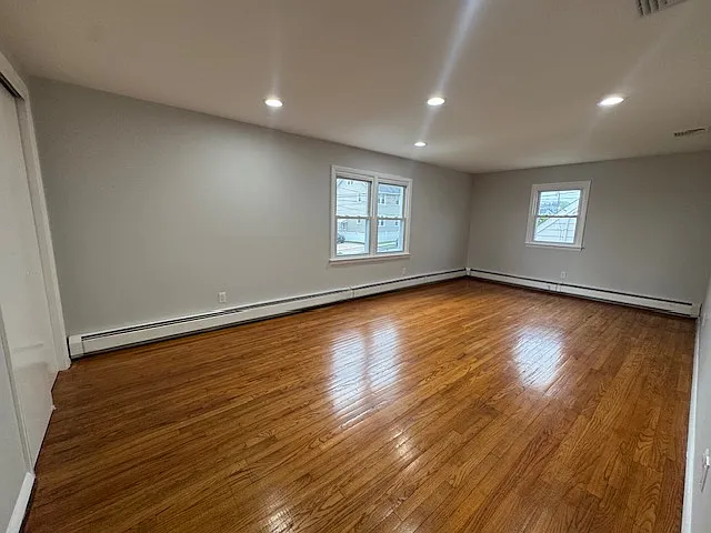 Bedroom 3 / Primary: Spacious and versatile room with ample space to accommodate a comfortable bedroom setup and a dedicated work-from-home area. Features abundant natural light, beautiful hardwood floors, and a closet for convenient storage.
