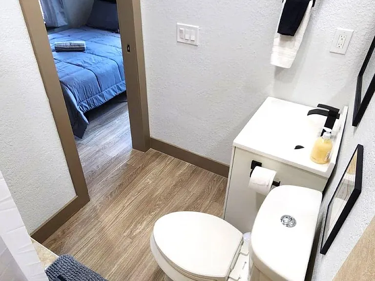 Compact bathroom with updated vanity, framed mirror, and easy-care flooring, conveniently located off the bedroom.