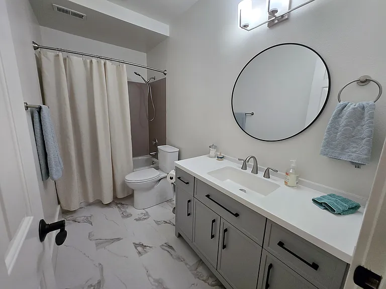 This brand new bathroom has plenty of cabinet and counter space and a curved curtain rod for more space in the shower. Bathroom exhaust fan provides great ventilation.