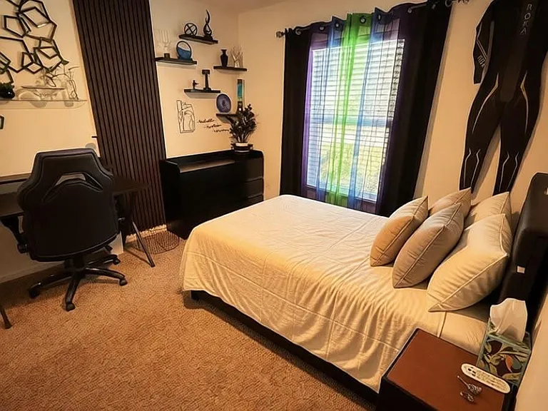 Furnished bedroom with a ceiling fan, window with blinds, desk workspace, and bedside table for everyday convenience.