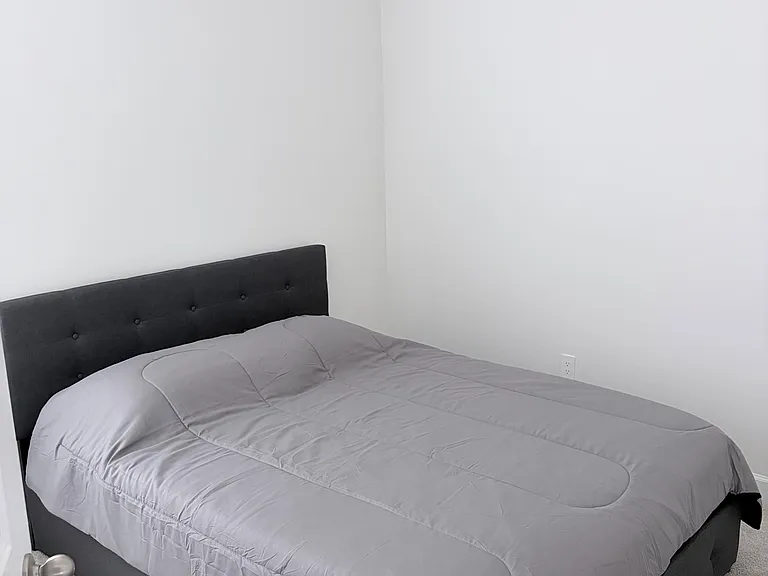 Clean, carpeted bedroom with neutral walls and space for a full/queen bed setup, offering a simple layout for easy furnishing