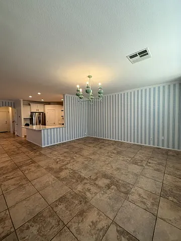 Bright, open-concept living room featuring custom designer wallpaper and statement lighting