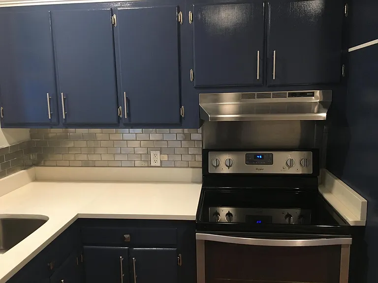 Remodeled kitchen - white quartz counter, stainless appliances, tile and sink. Real wood cabinets. Elegant & functional remod.
