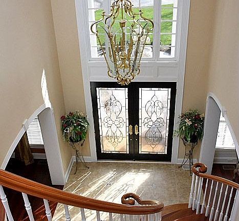 Elegant 2 story foyer features custom glass doors.