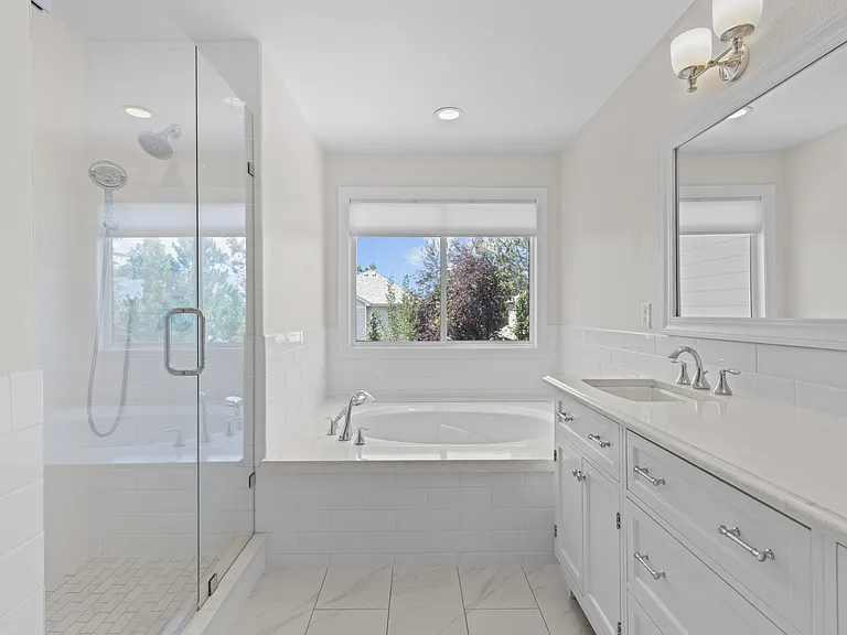 The spacious attached five-piece ensuite features dual vanities, a large soaking tub, and a functional layout designed for comfort and convenience.