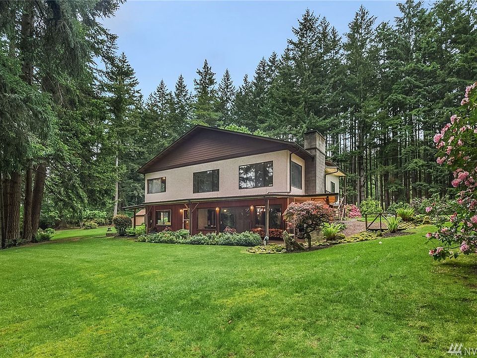 Home is nestled among towering firs, surrounded by generous lawns. The is the west elevation.
