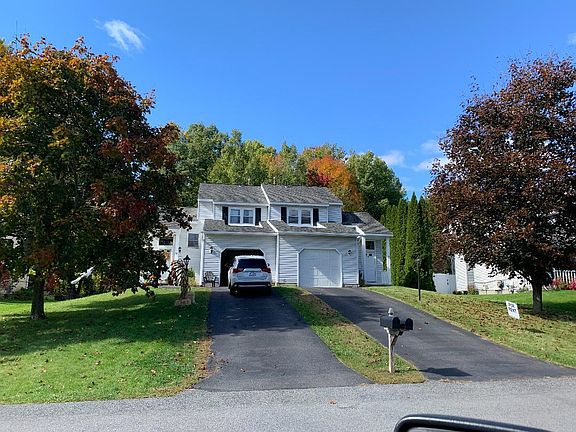 Front view showing driveway, lawn and trees on a beatiful fall day.