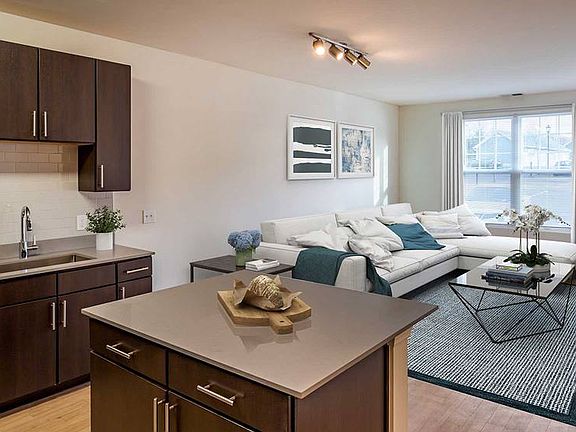 Newly renovated apartment homes feature kitchens with espresso cabinetry, grey quartz countertops, stainless steel appliances, grey tile backsplash, and hard surface flooring