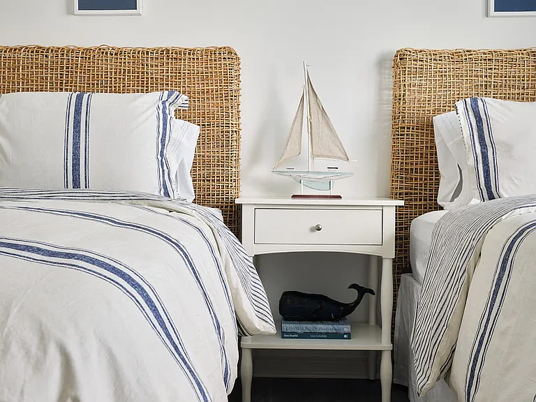 Charming third bedroom featuring two twin beds and a nightstand adorned with a sailboat accent.