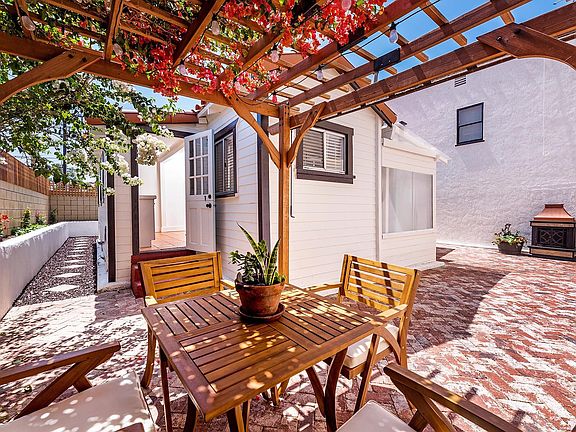 Brick patio with lighted pergola dining area and wood burning fireplace