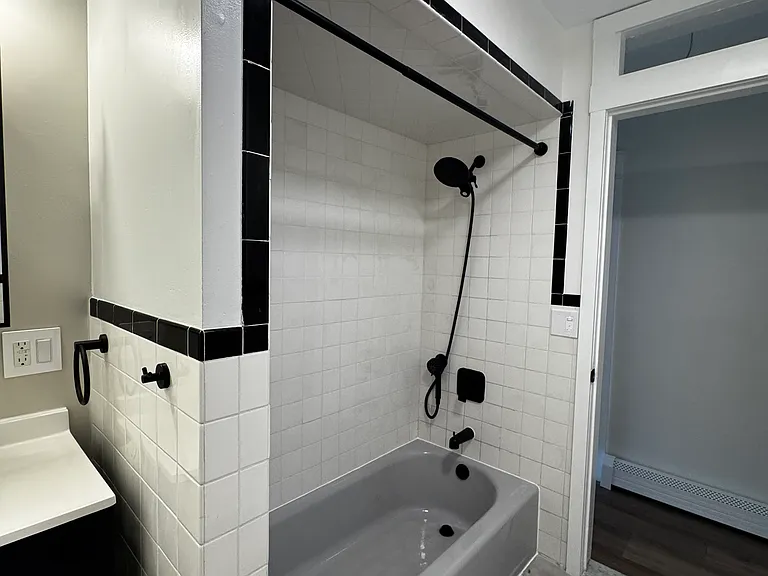 Bathroom (Actual Picture): Updated full bathroom with a tiled tub/shower, refreshed finishes, and convenient open shelving for extra storage
