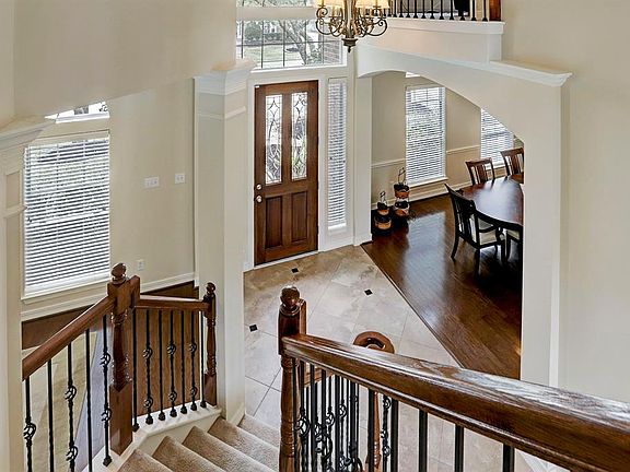 View from the upstairs looking down into the foyer shows the iron spindles and curved stairwell.