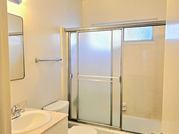 Bright, clean bathroom with sliding glass doors, window, air fan, medicine cabinet and more storage!