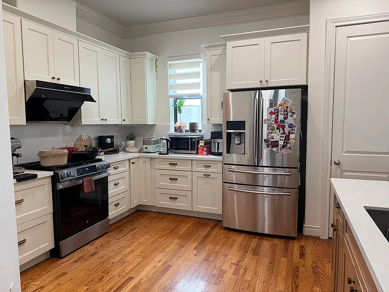 Renovated kitchen with new white cabinets and white countertop.