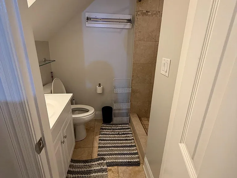 Full bathroom with tiled shower, vanity storage, and built-in shelving for everyday essentials.