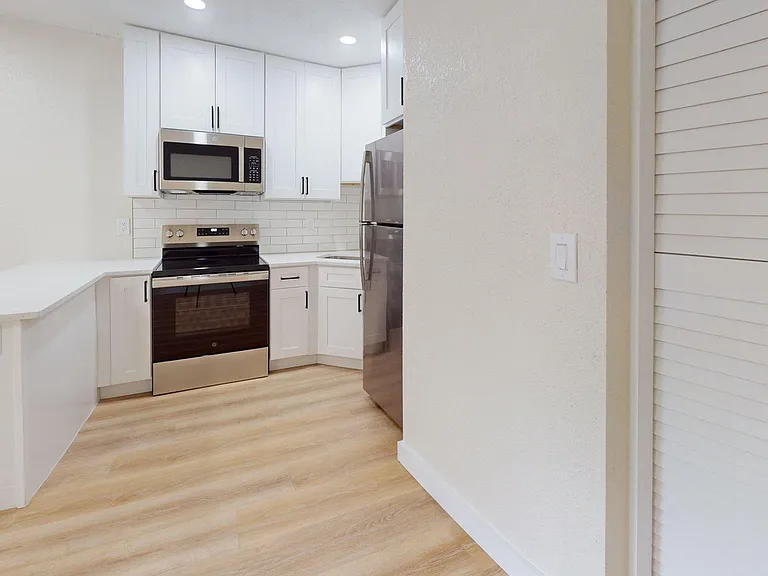 Contemporary kitchen with sleek stainless steel appliances, elegant white cabinetry, and warm wooden flooring. Contemporary kitchen with sleek stainless steel appliances, elegant white cabinetry, and warm wooden flooring.