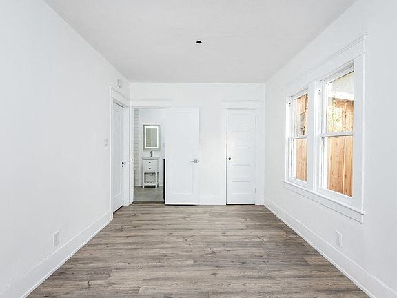 Bedroom with bathroom and large windows at 4141 Normal Avenue apartment homes in Los Angeles, California.